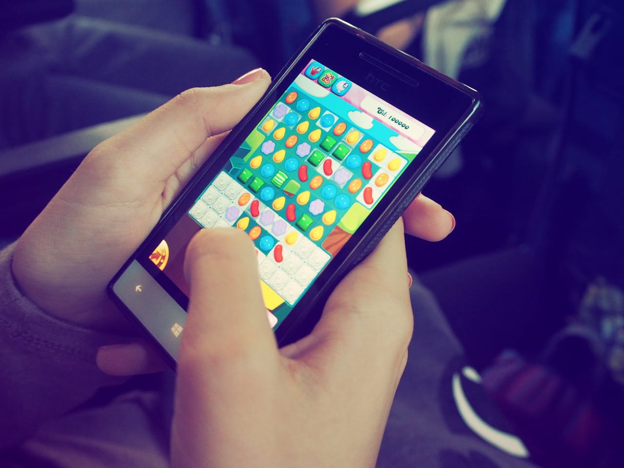 services-img Hands holding a smartphone with a colorful puzzle game on the screen, displaying modern technology.